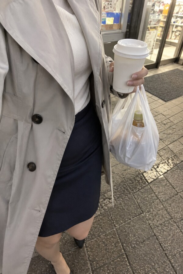 仕事帰りにコンビニの前でコーヒーと買い物袋を左手に持つなみ